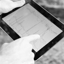 Hands showing a graph on a tablet in black and white