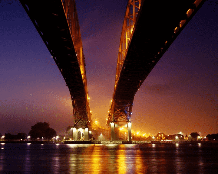 A red bridge going over a river as seen from underneath at dusk
